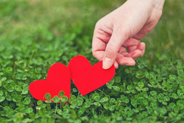 Obraz na płótnie Canvas Red paper hearts in green clover
