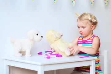 Little girl playing doctor role game with her toys