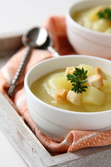 Creamy sweet potato soup with croutons and parsley in white bowl