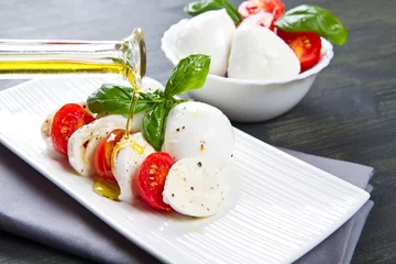 Rolgordijnen Tomato and mozzarella with basil leaves © Lsantilli