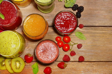 Fototapeta na wymiar Glasses of tasty fresh juice, on wooden table.