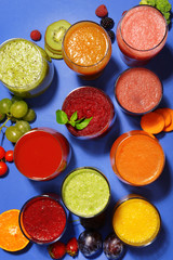 Glasses of tasty fresh juice, on blue background