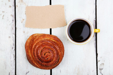 Composition of coffee, fresh bun and paper card