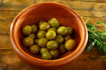 Green olives in the round bowl with branch
