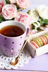 Colorful macaroons with cup of tea on wooden background