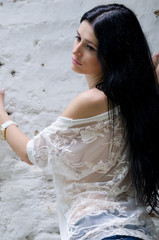 Fototapeta na wymiar Brunette girl in white shirt and jean posing near rock wall
