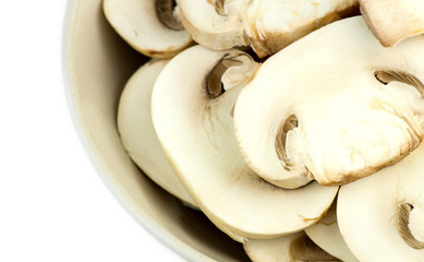 Macro closeup of sliced white common mushrooms in bowl isolated