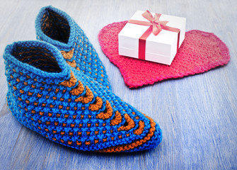 Old fashioned knitted slippers on a wooden background.