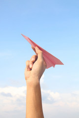 Hand holding pink paper aeroplane