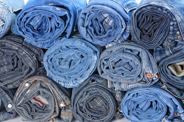 Stack of rolled colored jeans. Front view