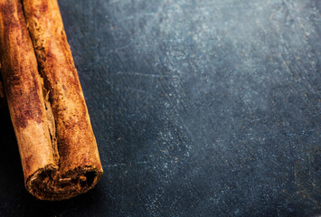 Bunch of cinnamon sticks close up on dark background with blank