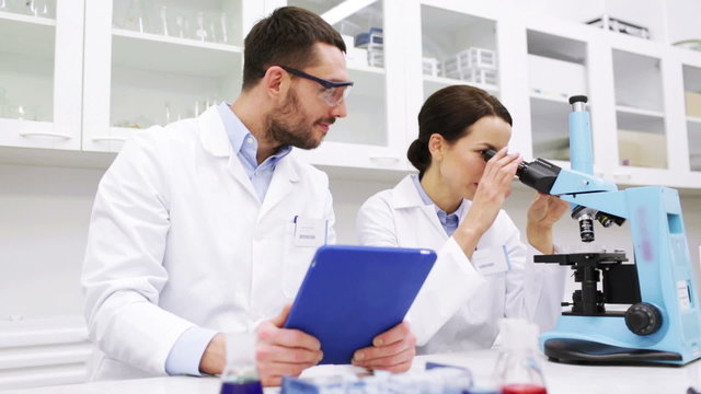 scientists with tablet pc and microscope in lab