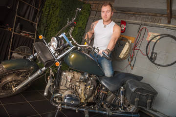 Obraz na płótnie Canvas Man sits on a motorcycle in the garage