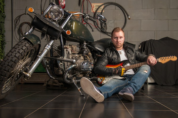 A man with a guitar sitting in a motorcycle