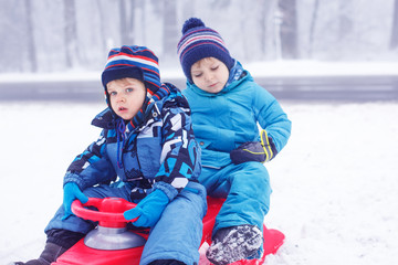 Happy family: two little twin boys having fun with snow in winte