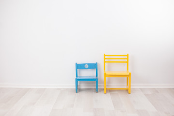 Two vintage child chairs on white wall