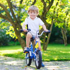 Fototapeta na wymiar Happy preschool boy riding his first bike