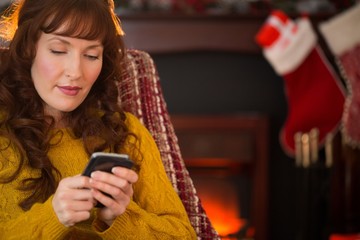 Cheerful redhead using mobile at christmas