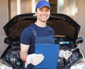 Mechanic holding a clipboard in front of a car