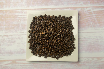 White square plate with a heap of coffee beans