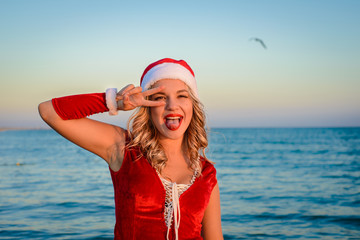 Obraz premium Happy and beautiful girl Santa Claus on the beach