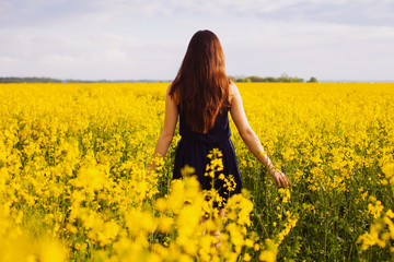 Naklejka na ściany i meble Girl enjoying rapeseed blooming on yellow meadow