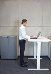 fit smart casual man  standing at height adjustment table