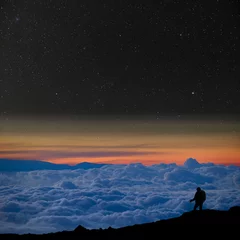 Foto op Canvas Lone climber above the clouds, looks at the starry night sky. © marcel