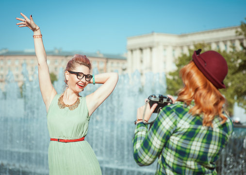 Two beautiful hipster girls taking pictures on an old camera