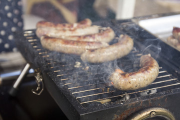 Tasty sausages cooking over the hot coals on a barbecue fire