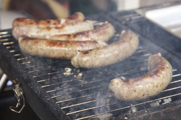 Tasty sausages cooking over the hot coals on a barbecue fire