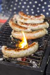 Tasty sausages cooking over the hot coals on a barbecue fire