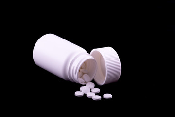 Pills in an open bottle on a black background