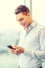 smiling businessman with smartphone in office
