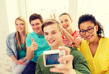 five smiling students taking picture with camera