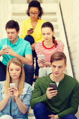 busy students with smartphones sitting on stairs