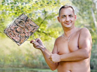 Приготовление пищи.  Мужчина на природе держит шашлык из рыбы