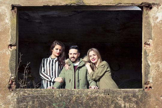 Chicos guapos posando en una ventana de una casa antigua