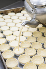 Pot filling egg pudding into puff of egg tart