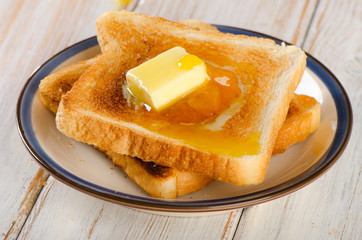 Slices toast bread with butter on a wooden background .