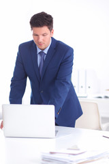 Confident successful young businessman leaning arms on his desk