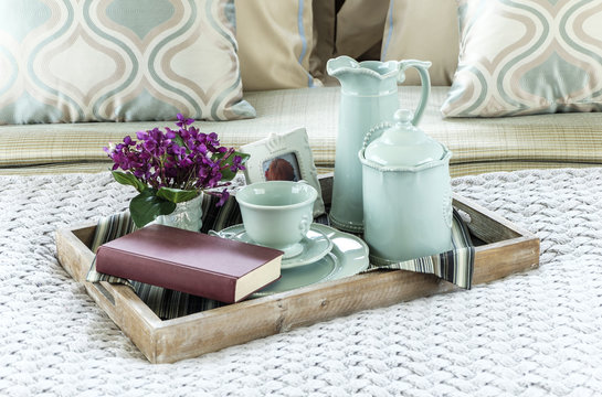 Decorative tray with book,tea set and flower on the bed