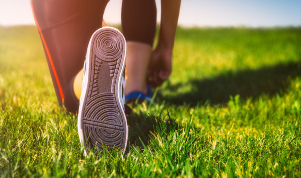 Girl running shoes closeup, green grass, woman fitness