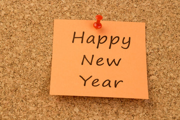 Orange sticky note on an office cork board. Happy New Year