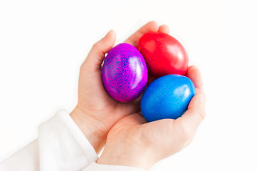 Child's hands holding 3 colorful easter eggs