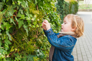 Obraz premium Adorable toddler boy playing with plants outdoors