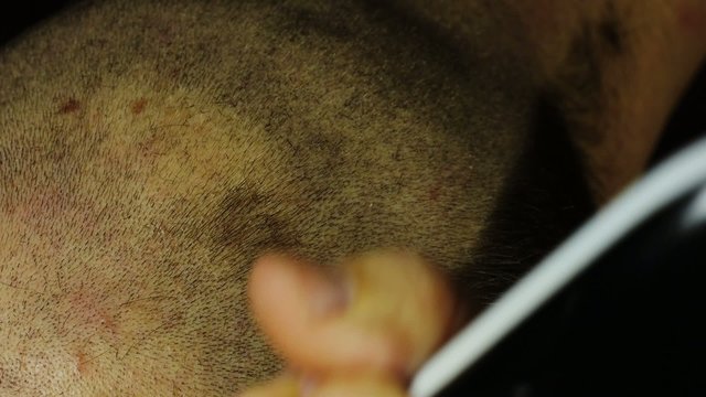 Man cuts his hair with electric razor.