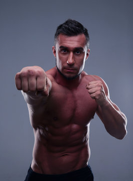 Fit man boxing over gray background