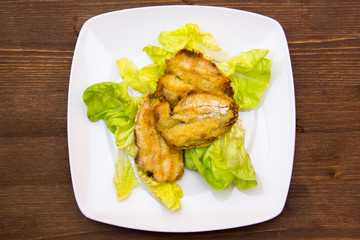 Fried fish on salad on wooden table seen from above