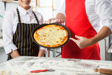 Chefs Presenting Delicious Pizza At Commercial Kitchen